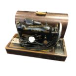A large oak cased Singer sewing machine, in locking domed top box with swing handle. (20.25in)