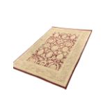 A contemporary oriental style rug having maroon field woven with stylised flowers & leaves, framed