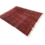 A Turkish Bokhara style rug woven with field of oval medallions on madder ground framed by