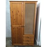 A reproduction pine wardrobe with mirrored door (absent)long door and three knobbed drawers,