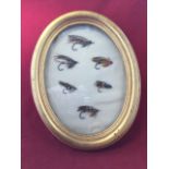 An oval gilt cased set of gut-eyed antique salmon flies. (11in x 8.75in)