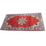 An eastern style rug woven with floral medallion & spandrels on red ground framed blue frieze of