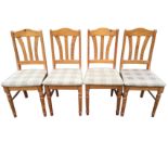 A set of four pine dining chairs with arched back rails above flared splats, the upholstered seats