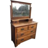 An Edwardian art nouveau oak dressing table, the back with bevelled plate on tapering supports above