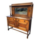 An Edwardian oak sideboard with bevelled mirror to back in lozenge moulded frame beneath a shelf