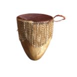 A large African skin drum, the circular top tightened by twisted thongs, above a skin base with