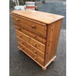 A reproduction pine chest of drawers, the rectangular moulded top above five long knobbed drawers,