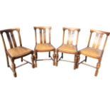 A set of four 50s oak dining chairs having twin splats with stylised carving above drop-in