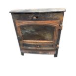 A bowfronted cast iron stove with arched glazed door above a drawer with shaped apron. (21.25in x