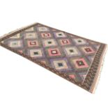 A large kilim woven with a diamond patterned field framed by brown geometric border with green