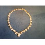 A carved Edwardian ivory necklace of 15 graduated pairs of elephants alternating with beads, and
