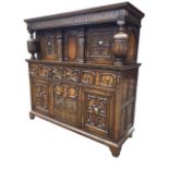 A large carved oak court cupboard, with moulded cornice above a blind fretwork frieze raised on
