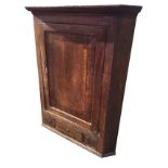 A nineteenth century oak corner cupboard with moulded cornice above a mahogany crossbanded door