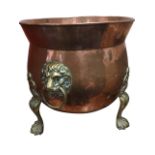 A cauldron shaped copper log bin with flared rim above hammered body mounted with lionmask ring