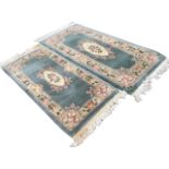 A pair of similar Chinese thick pile wool rugs, with pastel floral ivory friezes on green fields,