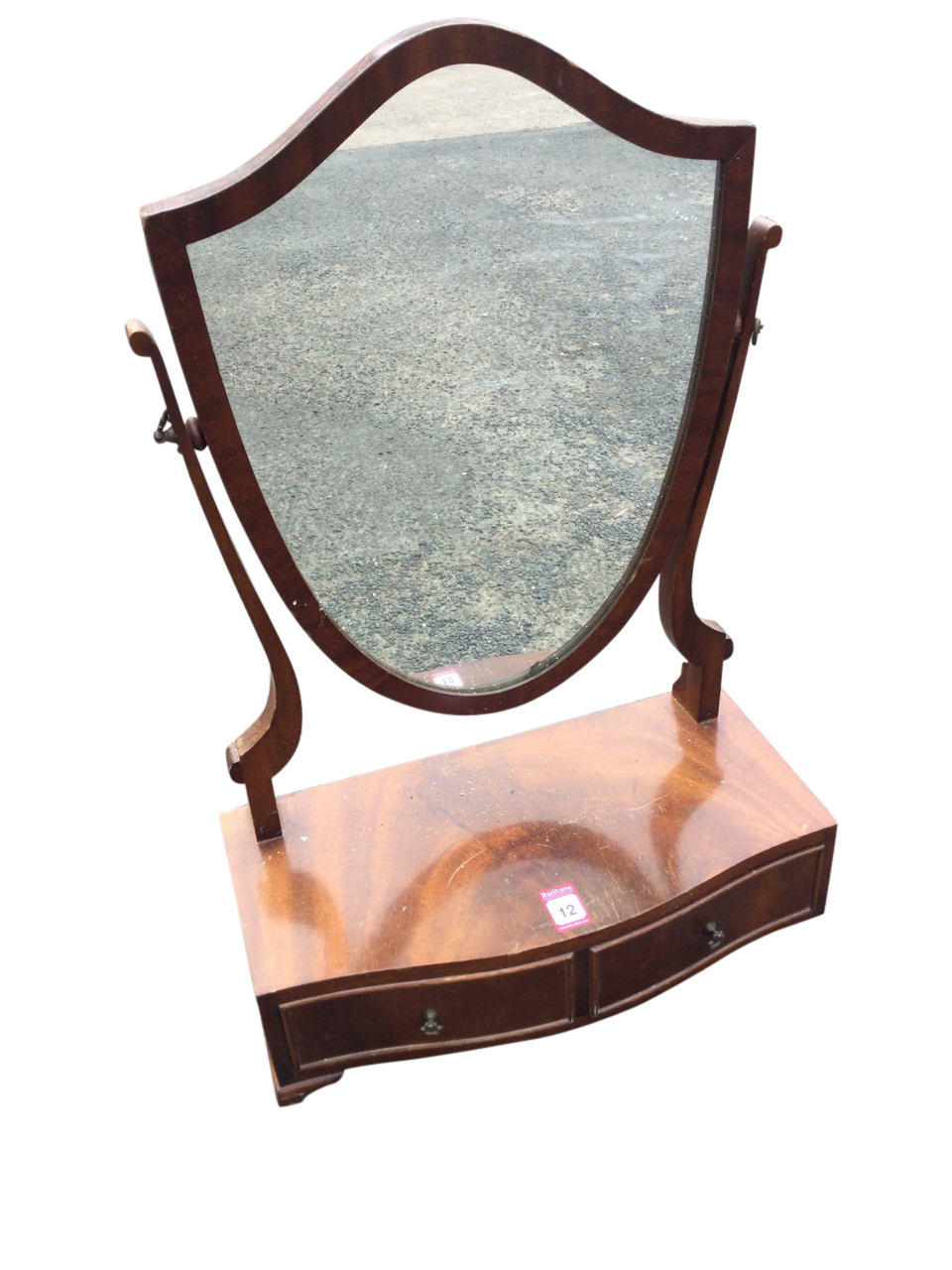 A mahogany dressing table mirror with shield shaped plate on tapering supports above a bowfronted