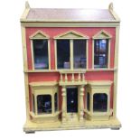 A C20th painted and papered red brick dolls house, the hinged front elevation with bay windows,