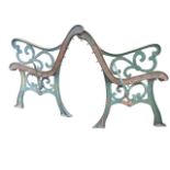 A pair of cast iron garden bench ends with scrolled arms on channelled sabre legs - no slats. (
