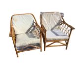 A pair of cane conservatory armchairs with loose linen upholstered cushions, the arms with stick