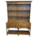 An oak dresser, the delft rack with moulded cornice and shaped apron above open shelves with