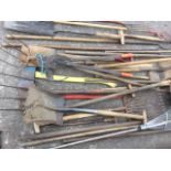 A quantity of garden tools including rakes, forks, shovels, a bolt cutter, a yard brush, hoes, pitch