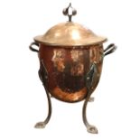 An art nouveau hammered copper coal bin & cover with hand-wrought riveted iron mounts, raised on
