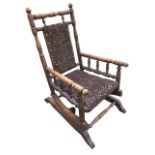 A childs American rocking chair with ring-turned frame to back around an upholstered panel with