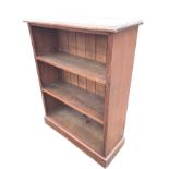 A stained late Victorian open bookcase with adjustable shelves framed by reeded stiles, supported on
