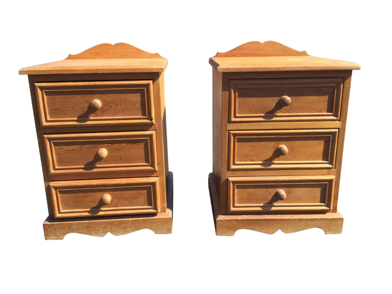 A pair of pine bedside cabinets with shaped upstands to moulded tops, each having three panelled