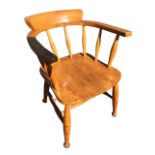 An elm captains chair, the rounded bow back on spindles above a solid seat, raised on turned