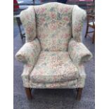 A Georgian style wing armchair with arched back and padded splayed arms above a loose cushion