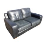 A charcoal grey leather two-seater sofabed, with loose cushions and padded arms above a sprung seat.