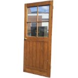 A pine door with glazed top above a tongue & grooved panel, mounted with brass knobs. (31.75in x