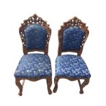 A pair of carved hardwood chairs with pierced scrolled frames to padded backs, the sprung