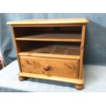 A pine cabinet with moulded top above open shelves and knobbed drawer, raised on bun feet. (22.5in x