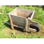 An ancient old wheelbarrow with angled pine boarded box on elm shafts, having later(?) rubber