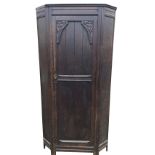 A C20th carved oak wardrobe with panelled canted corners, the tongue & grooved door with foliate
