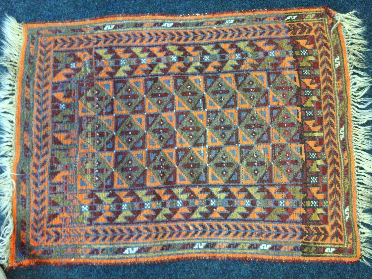 A Turkish rug woven with field of triangular & square panels framed by border of winged bat type