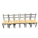 A set of six contemporary stained kitchen chairs with ladder backs above rush seats, raised on