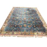A eastern style carpet woven with busy blue floral field with serrated leaves and linked