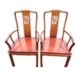 A pair of Chinese hardwood armchairs, the shaped backs with rectangular splats having pierced panels