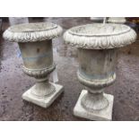 A pair of composition resin garden urns with lozenge moulded rims on fluted tapering bodies, with