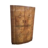 A deco walnut wardrobe of scalloped bowfronted outline having two doors enclosing an interior with