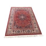 An Indian rug woven with busy red floral field framing a central scalloped blue floral medallion