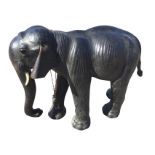 A C20th leather mounted Liberty style elephant, the beast with glass eyes modelled walking with