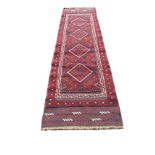 A Turkish runner woven with red field of four diamond shaped medallions with blue hooked borders,