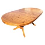A pine dining table with spare leaf, the moulded top with rounded ends supported on turned columns