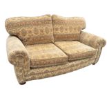 A contemporary tapestry upholstered two-seater sofa with loose cushions and rounded arms raised on