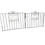 A pair of wrought iron driveway gates with vertical bars in rectangular frames, having scrolled