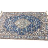 A Persian rug woven with oval foliate medallion on blue field with linked foliage, the spandrels